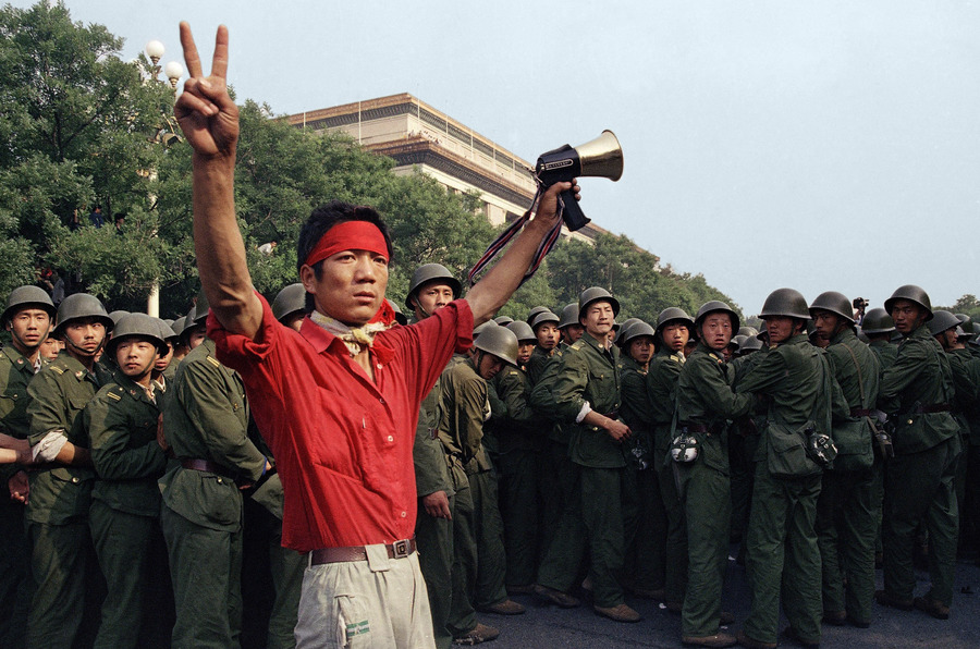A protester tries to rally support as soldiers emerge from the Great Hall of the People just hours before gunfire erupted around Tiananmen Square. © 1989 AP Photo/Mark Avery