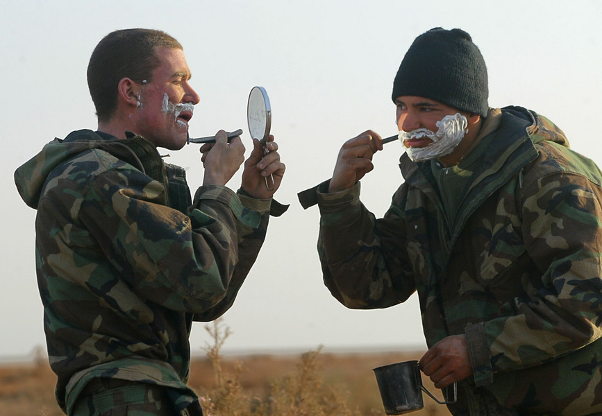 Cpl. Ryan Hamilton of Dana Point, and L/Cpl. Eric Young of Orange share a mirror as they shave with the US Marine Corps' Regimental Combat Team 5 in Iraq. © 2003 Mark Avery/Orange County Register