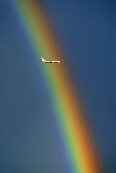 An airliner on approach to John Wayne Airport intersects with a rainbow over the city of Tustin. © 2005 Mark Avery/Orange County Register