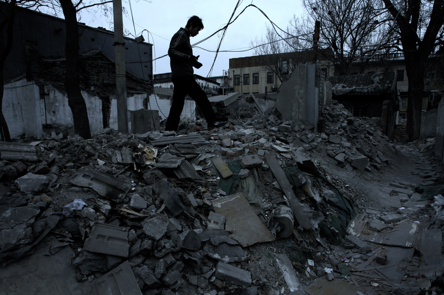 A Chinese man climbs over debris from demolition during the renovation of Beijing's Dazhalan neighborhood. © 2006 by Mark Avery